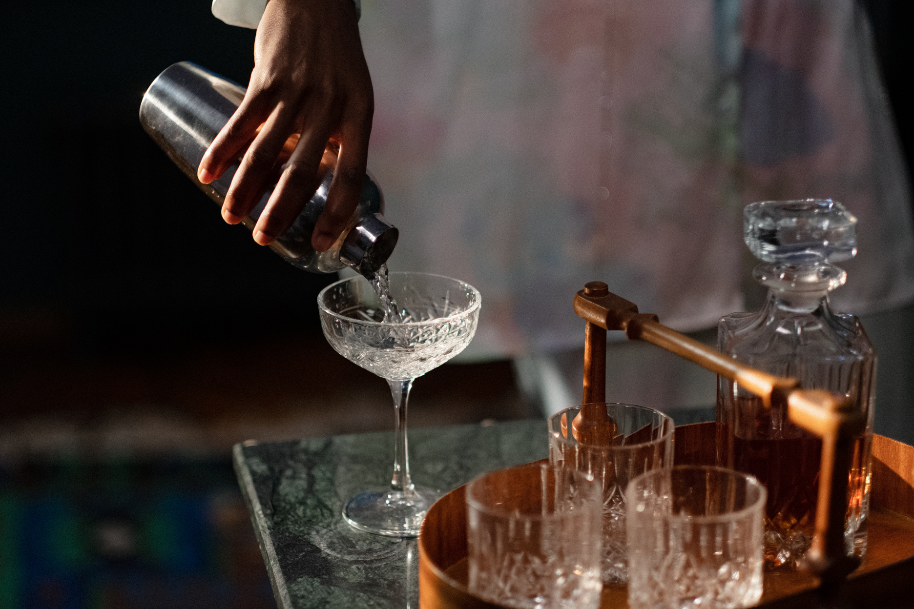 Hand pouring cocktail into glass from shaker